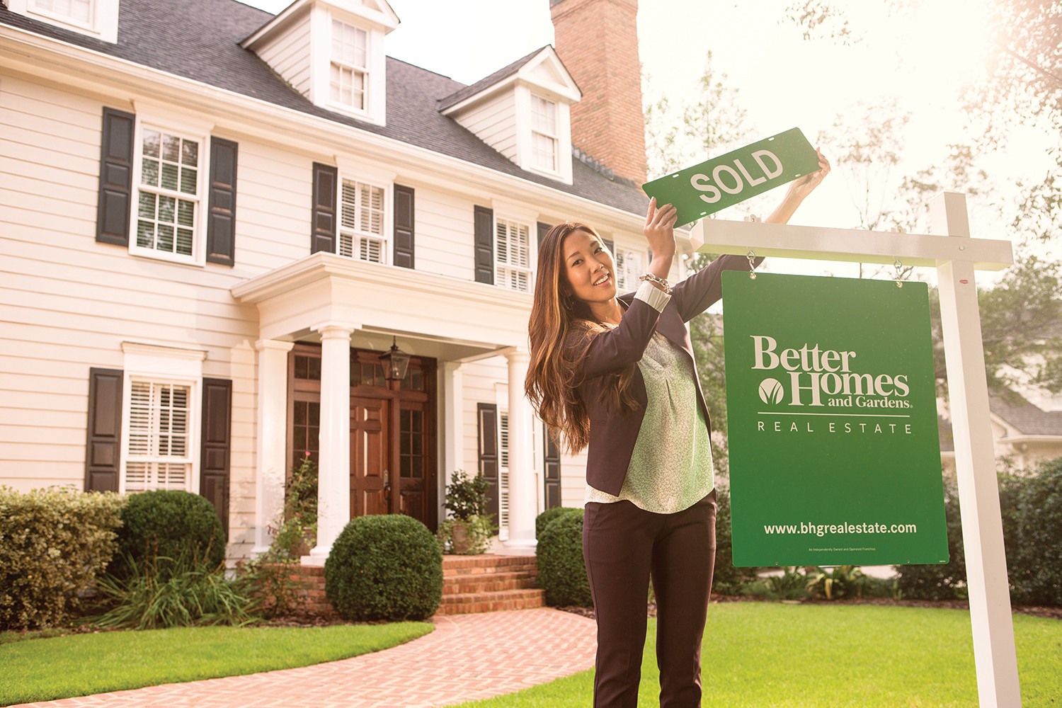 Better Homes and Gardens Real Estate agent placing sold sign